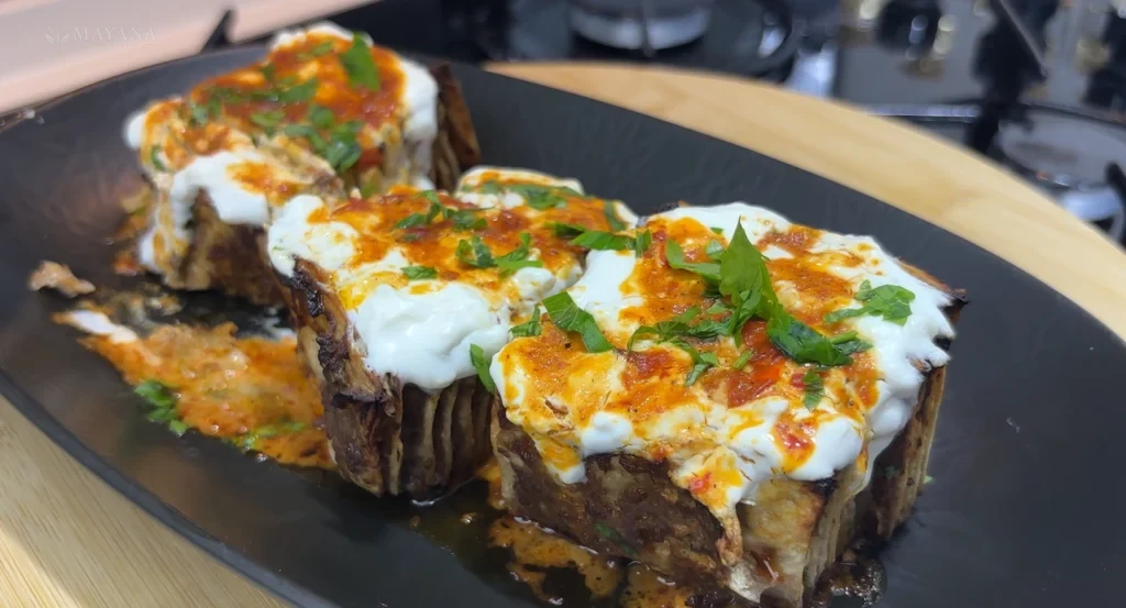 Sarımsaklı yoğurt üzerinde tereyağlı salçalı sosla servis edilen lavaş kebabı