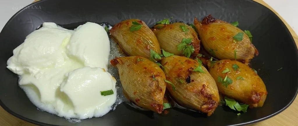 Fırın tepsisinde salçalı sosla pişmiş kıymalı soğan dolması
