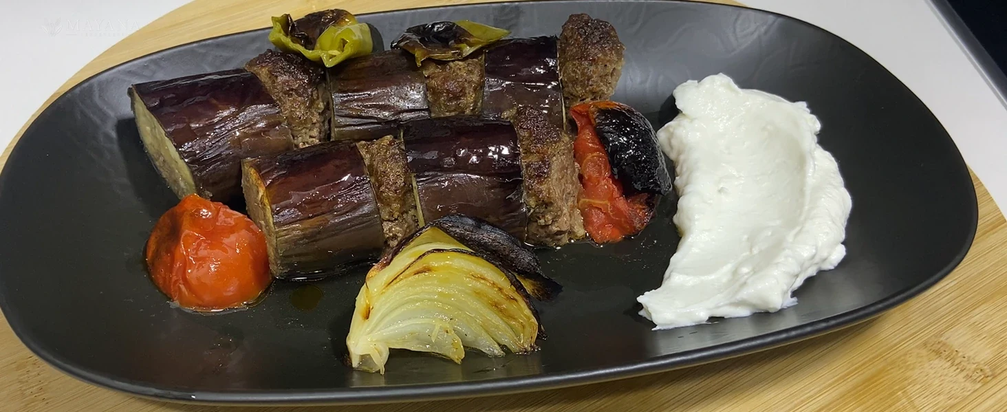 Fırın tepsisinde köfte ve patlıcan dilimleriyle hazırlanmış patlıcan kebabı