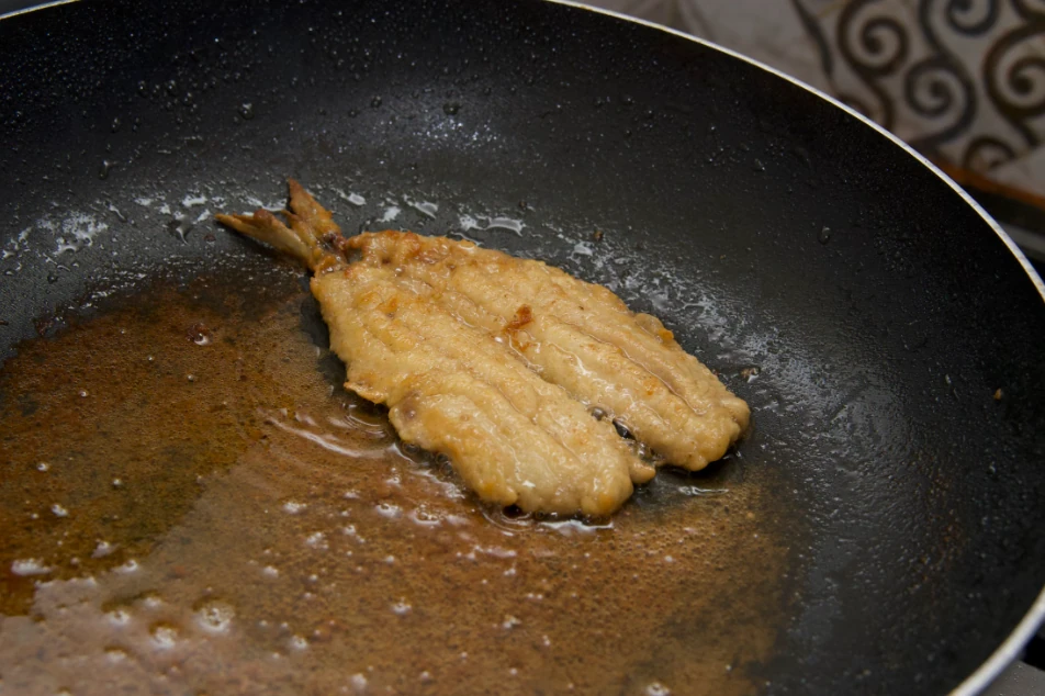 Fish fillet cooked in a pan with golden-brown, crispy skin